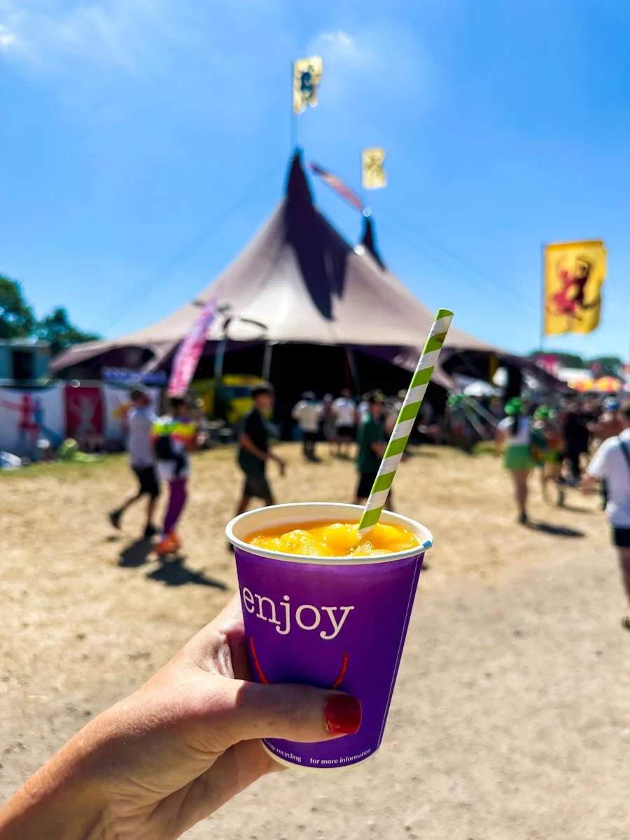 Hand-holding slushy cocktail at a festival that says enjoy